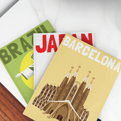 Collection of custom travel photo books, showcasing destination covers for Barcelona (Sagrada Familia), Japan, and Brazil.